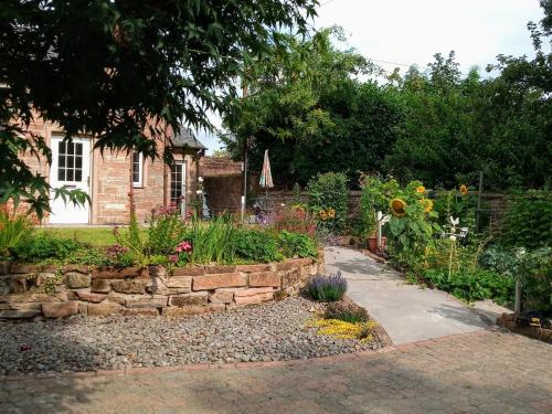 un giardino di fronte a una casa con un muro di pietra di Laurieknowe Coach House a Dumfries