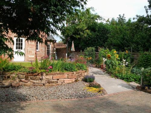 a garden in front of a house with a stone wall at Laurieknowe Coach House in Dumfries