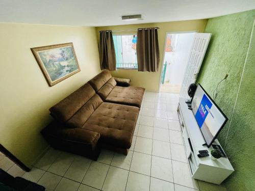 a living room with a brown couch and a television at Morada do Mar Arraial do Cabo in Arraial do Cabo