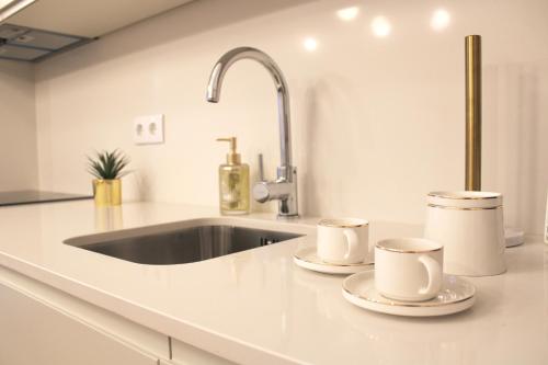 um balcão de cozinha com duas chávenas e um lavatório em Aliados Sunny Flat no Porto