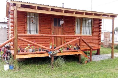 a log cabin with flowers and plants in front of it at Cabaña meolos in Tandil