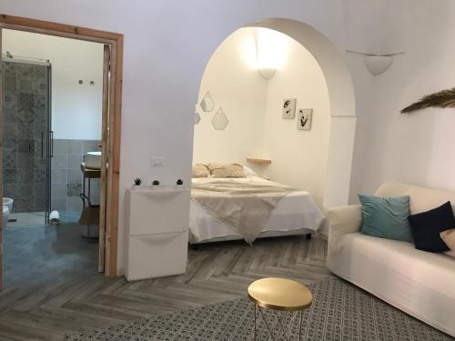 a white bedroom with a bed and a couch at L’alcova del centro in Pantelleria