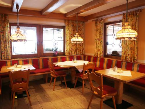 a restaurant with two tables and chairs and windows at Gasthof Pension Madseiterhof in Tux