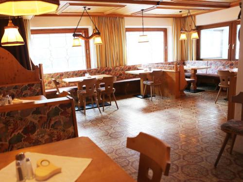 a dining room with tables and chairs and windows at Gasthof Pension Madseiterhof in Tux