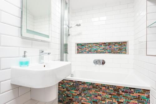 a white bathroom with a sink and a tub at Polly's Folly in Swanage