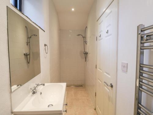 a white bathroom with a sink and a mirror at Castle Mill in Newport Pembrokeshire