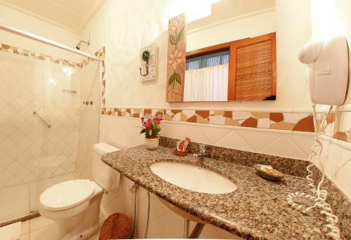 uma casa de banho com um lavatório, um WC e um espelho. em Pousada Burundanga em Itacaré