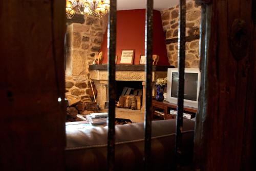 a living room with a stone fireplace and a television at Posada Rural Ochohermanas in Las Fraguas