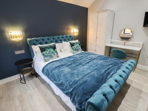 a bedroom with a large bed with a blue headboard at Honeysuckle in Hull