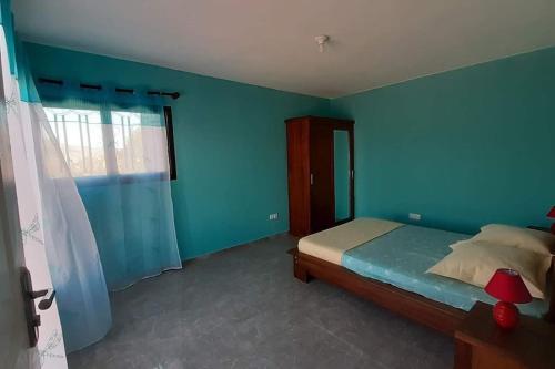 Dormitorio azul con cama y ventana en villa luxueuse et meublée plus de 280 m², en Antananarivo