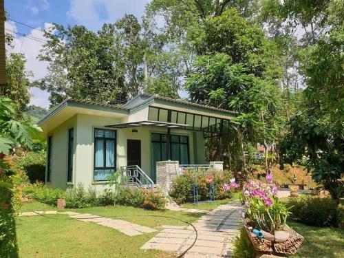 a green house with a garden and flowers at Snapper House in Khao Lak