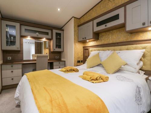 um quarto com uma grande cama branca com cobertores amarelos em Nordene em Cockermouth