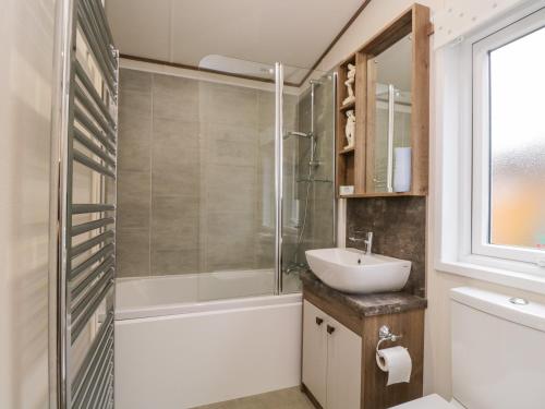 uma casa de banho com uma banheira, um lavatório e um chuveiro em Nordene em Cockermouth