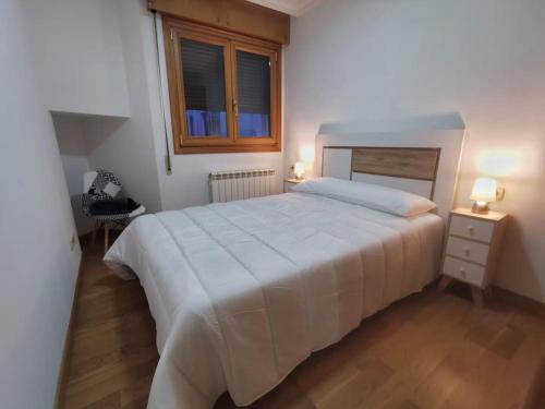 una camera da letto con un grande letto bianco e una finestra di Castrelos, Vigo, diseño a Vigo