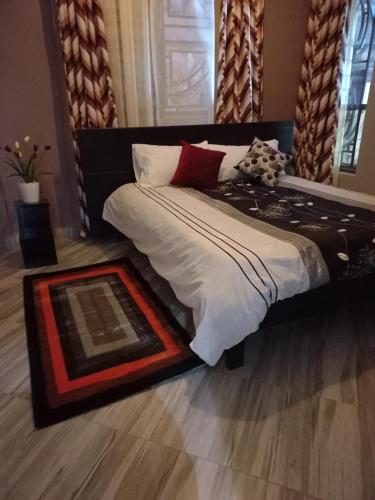 ein Schlafzimmer mit einem großen Bett mit weißen und roten Kissen in der Unterkunft nostiQ homes in Kampala