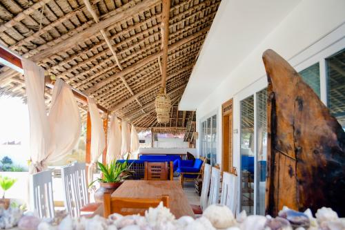 a dining room with a table and a surfboard at Villa Thamani Zanzibar in Pwani Mchangani
