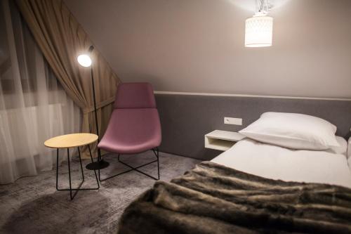 a bedroom with a bed and a purple chair at Hotel ZAWRAT Ski Resort & Spa in Białka Tatrzanska