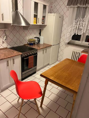 a kitchen with a red chair and a wooden table at Mieszkanie z widokiem na Görlitz in Zgorzelec