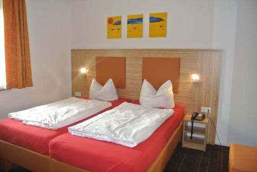 a bedroom with two beds with red sheets and white pillows at Hotel Art-Ambiente in Hagen