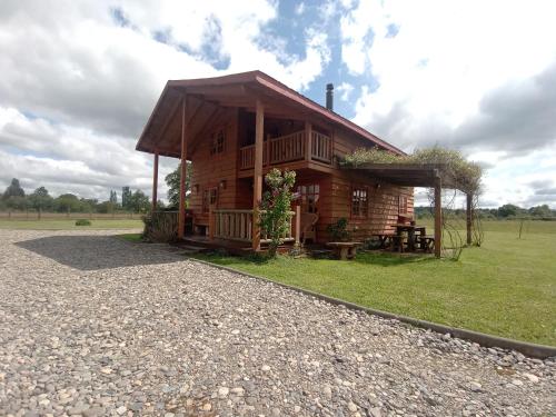 a log cabin with a porch and a grass field at Casa del rio in Radal