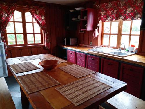 a kitchen with red cabinets and a wooden table at Casa del rio in Radal