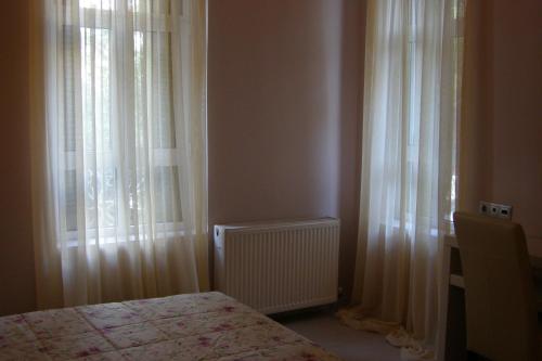 a bedroom with white curtains and a bed and a window at room "butterfly" in a neoclassical house in Kastoria