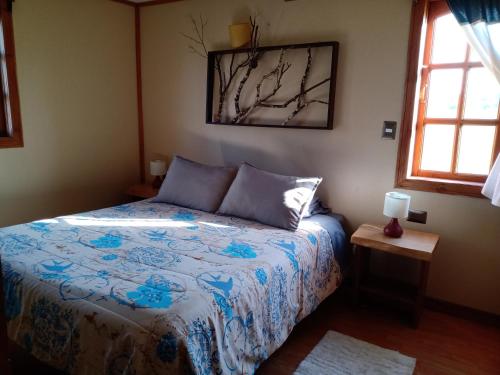 a bedroom with a bed with a blue comforter at Casa del rio in Radal