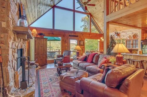 a living room with leather furniture and a stone fireplace at stayNantahala - Smoky Mountain Cabins in Aquone