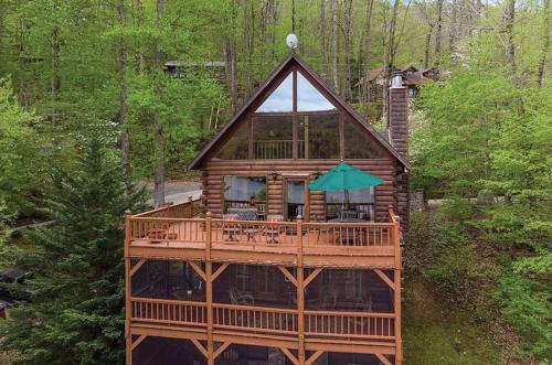 a house with a wrap around deck with an umbrella at stayNantahala - Smoky Mountain Cabins in Aquone