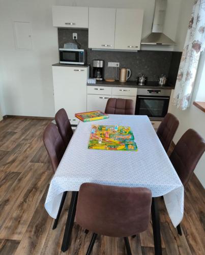 a kitchen with a white table with brown chairs at Penzion Šumava - APARTMÁN in Horní Planá