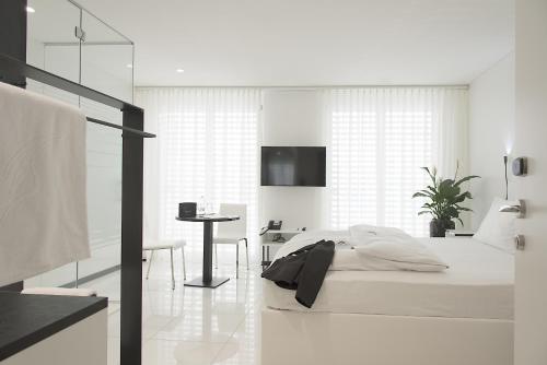 a white bedroom with a bed and a desk at Residence Thessoni Home, Hotel & serviced apartments Zürich in Regensdorf