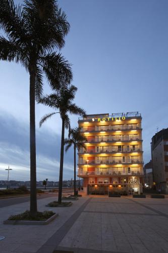 a large building with palm trees in front of it at Apartamentos Rotilio in Sanxenxo