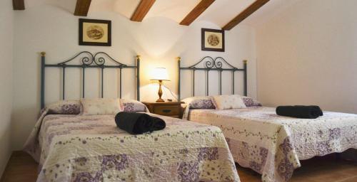 Dos camas en una habitación con dos sombreros negros. en Casa el angel, en Castril