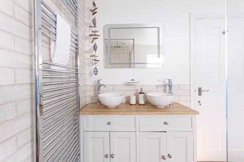 a bathroom with two sinks and a mirror at Trelights Port Issac in Saint Endellion