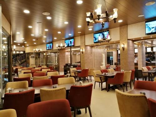 un ristorante con tavoli, sedie e televisori di La Place Hotel a Zahlé