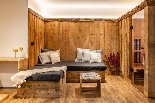Bellevue Bruneck - Suites & Lofts في برونيكو: غرفة نوم بحائط خشبي مع سرير وطاولة