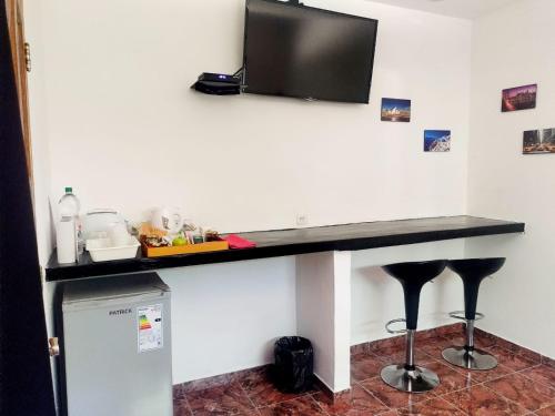 a desk with a television on a wall with stools at Posada Quinta Pata in Ezeiza