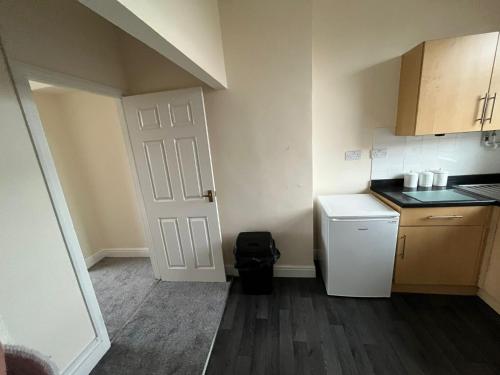 een kleine keuken met een witte deur en een koelkast bij conway flat in Newport