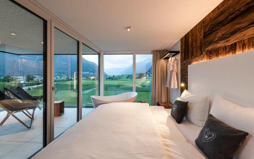 ein Schlafzimmer mit einem großen Bett und einem großen Fenster in der Unterkunft Bellevue Bruneck - Suites & Lofts in Bruneck