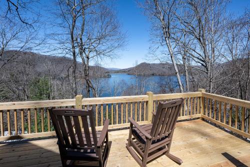 two chairs sitting on a deck with a view of a lake at stayNantahala - Smoky Mountain Cabins in Aquone