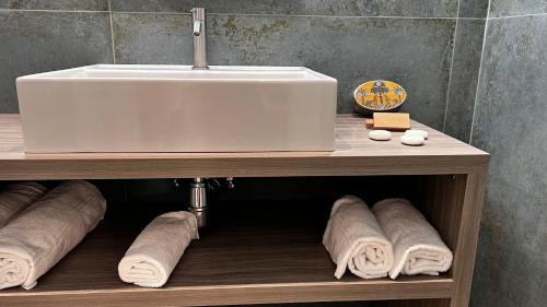 baño con lavabo y toallas en un estante en Patriziella 4 Rooms, en Sorrento