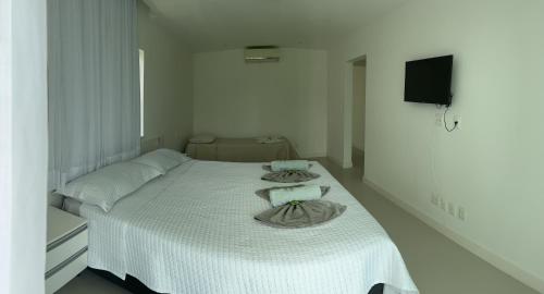 een witte slaapkamer met een bed met handdoeken erop bij Venha se hospedar no Paraíso de Guarajuba in Camaçari