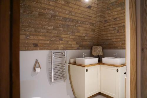 een badkamer met 2 wastafels en een bakstenen muur bij Hare's View in Rhayader