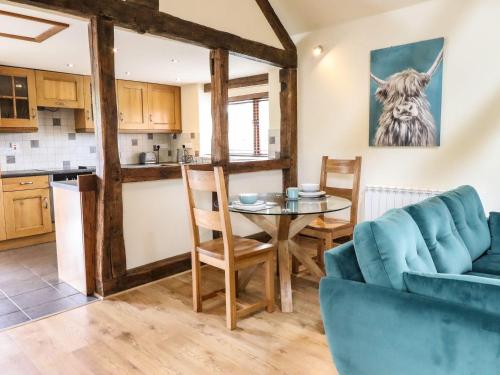 a kitchen and living room with a table and a couch at Beudy Bach in Aberhafesp