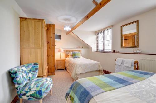 a bedroom with two beds and a chair in it at Bryncylla Cottage in Llangurig