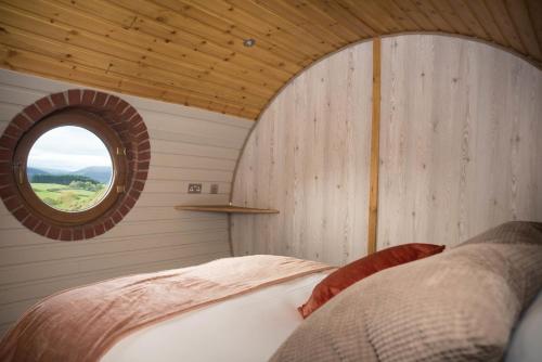 1 dormitorio con cama y ventana redonda en Foxes View, en Rhayader