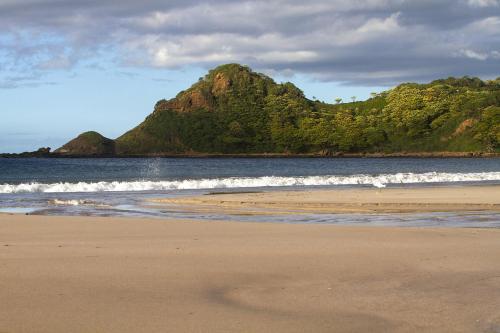 a sandy beach with a mountain in the background at Morgan's Rock in San Juan del Sur