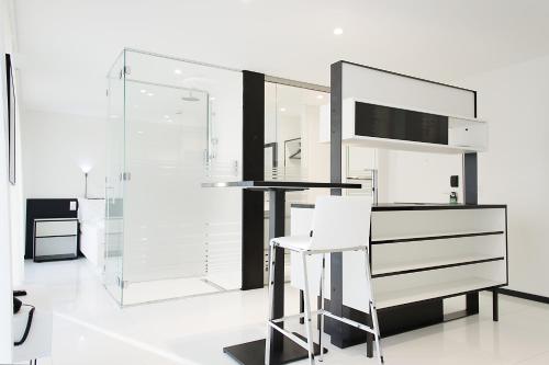 a white kitchen with a counter and a stool at Residence Thessoni Home, Hotel & serviced apartments Zürich in Regensdorf