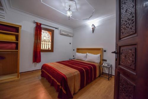 a bedroom with a bed with a red blanket and a window at Riad Assia in Marrakesh