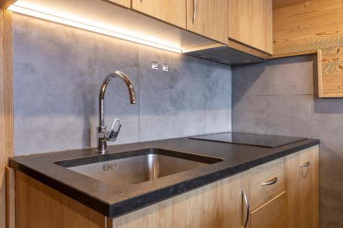 a kitchen with a stainless steel sink and wooden cabinets at Val Thorens - Cosy Duplex Silveralp 004 in Val Thorens